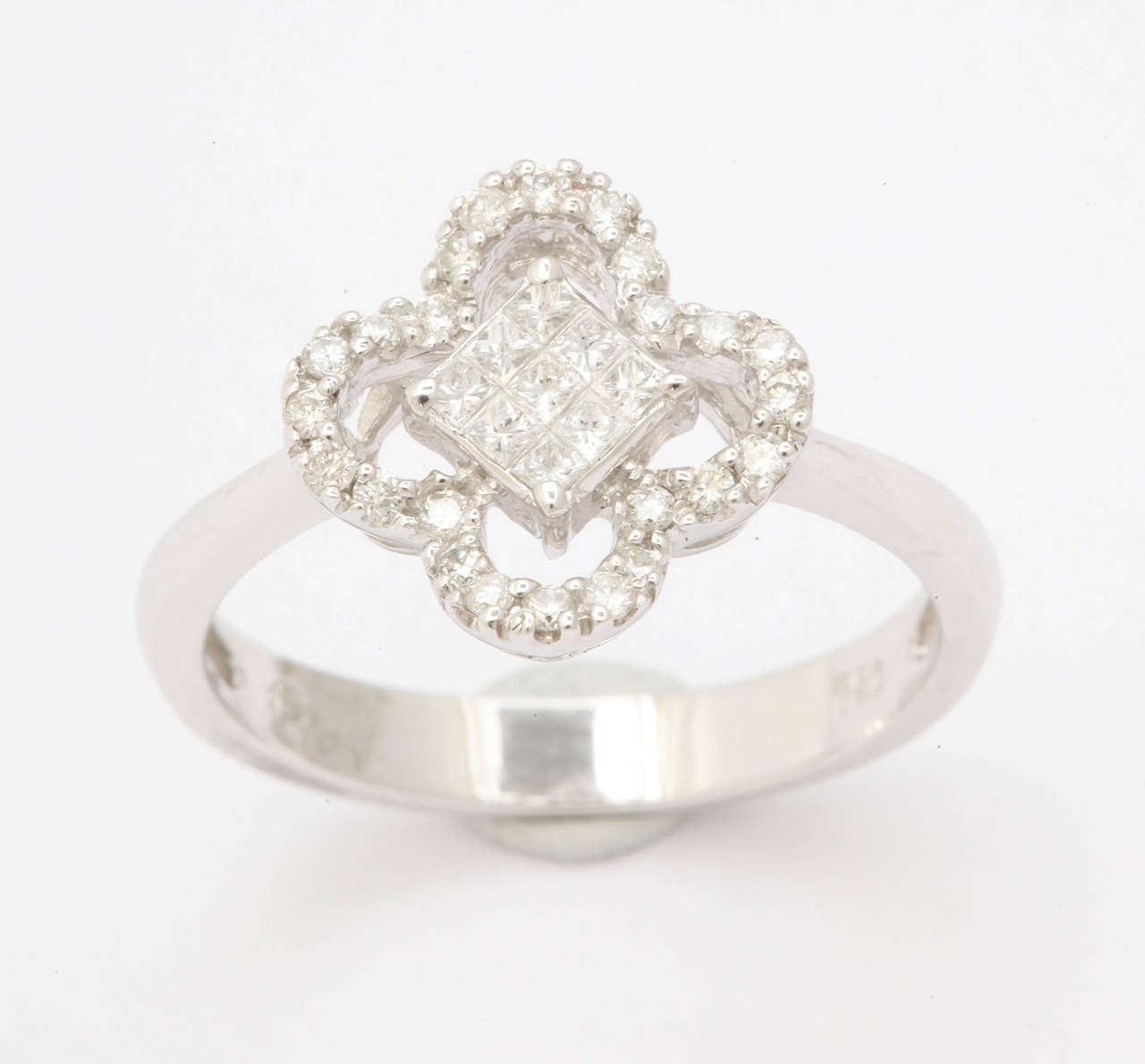 The center of this 18 kt white gold ring holds 9 square radiant cut invisibly set diamonds. The center is surrounded by 4 arches of round white diamonds. Total diamond weight is .38 ct. A simply lovely ring for any occasion.