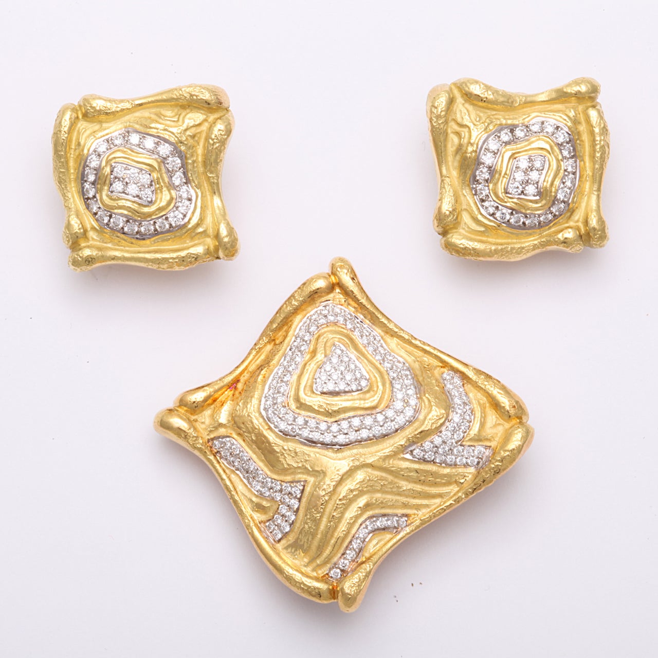 A great free form 18 kt gold pin set including matching clip earrings with diamond decoration. Approx 1.4 oz. Earrings measure 7/8 th of an inch square