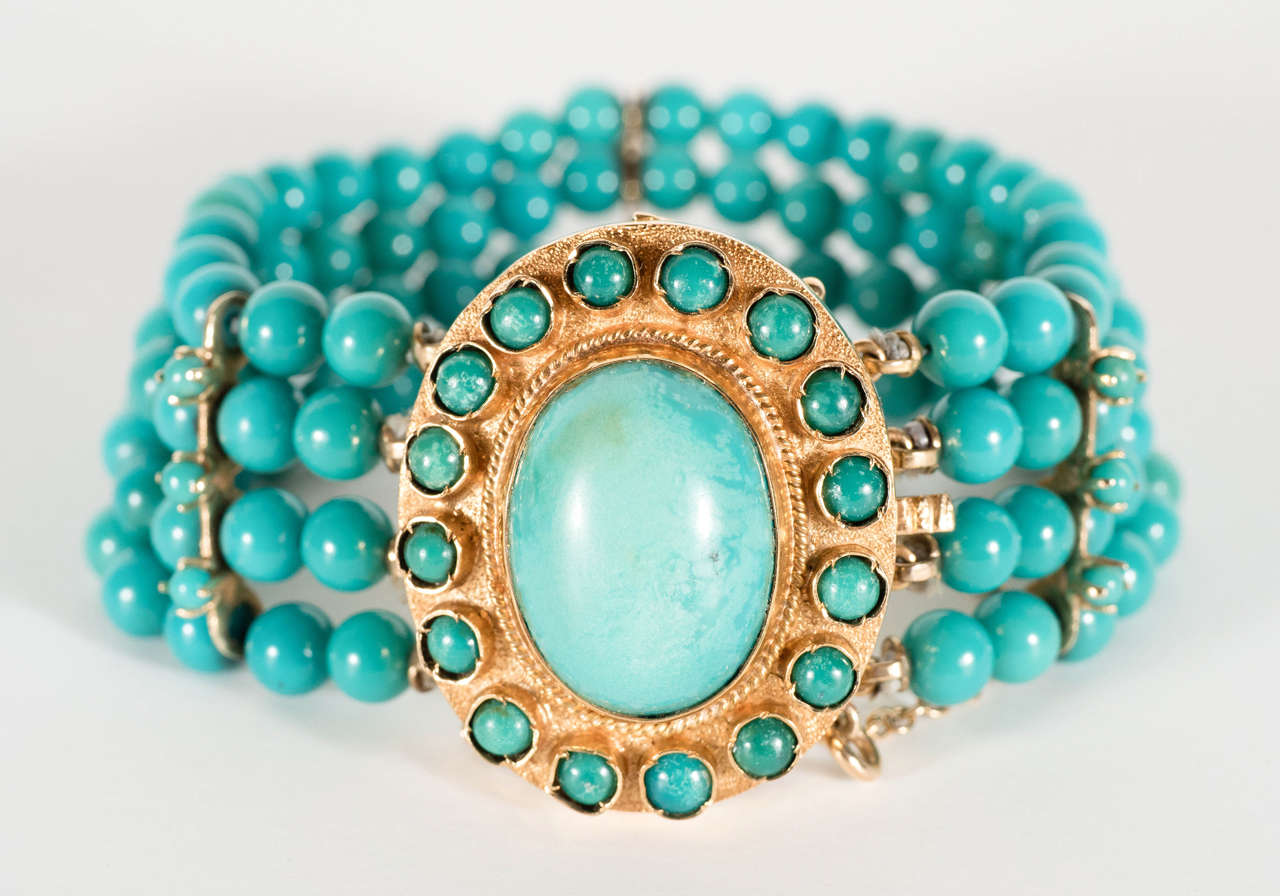 This bracelet features a center oval turquoise clasp set in 14 carat yellow gold with a surround of 14 round turquoise beads . The bracelet consists also of 4 strands of finely matched turquoise beads with three support dividers in 14 carat also set