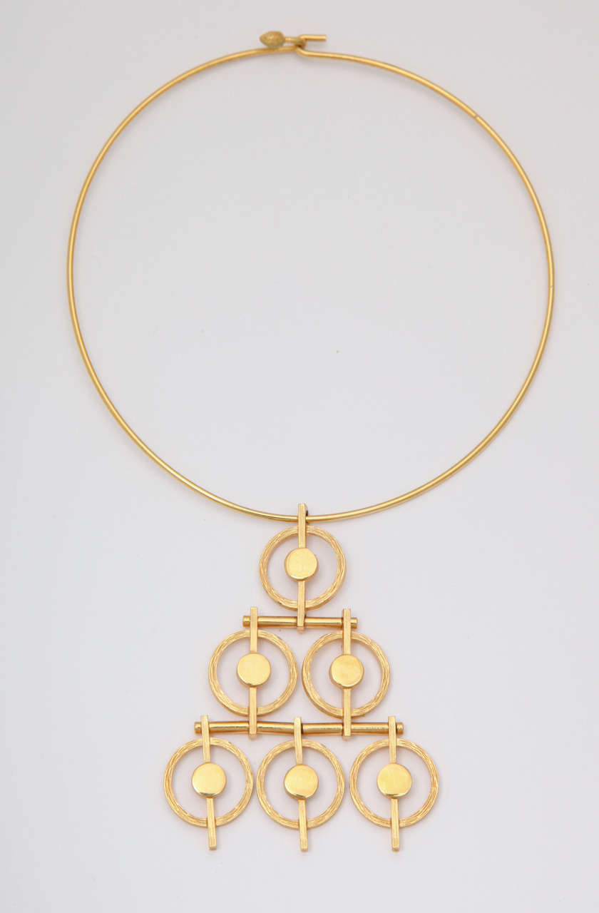 Goldtone wire choker necklace with a pyramid shaped medallion of circles.
Choker diameter is 5