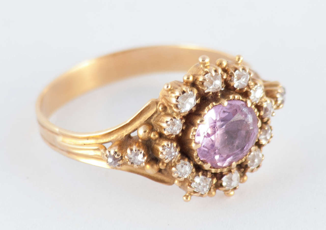 Fantastic 18K ring set with a central pink topaz surrounded by diamonds. A beautiful ring to wear day or night. The ring is a size 8 3/4 and can be resized. It measures approximately 1/2