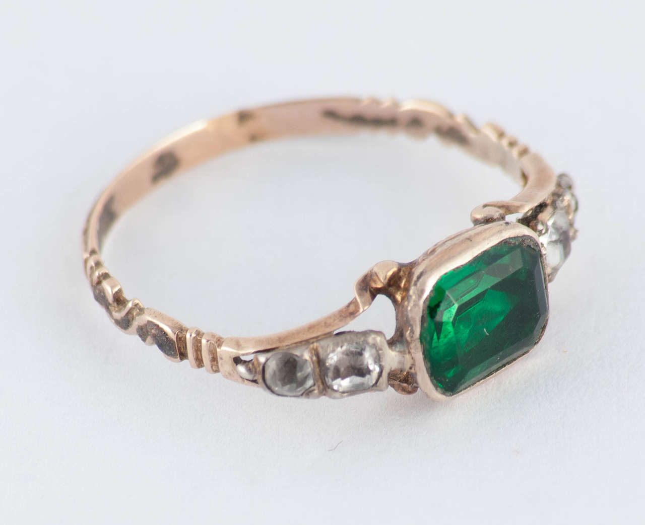 Georgian ring of green paste in a basket setting flanked by two clear pastes on each side. Paste is colored or clear glass, often lead or flint, cut in the same fashion as gemstones and used as a substitute especially while traveling. Antique paste