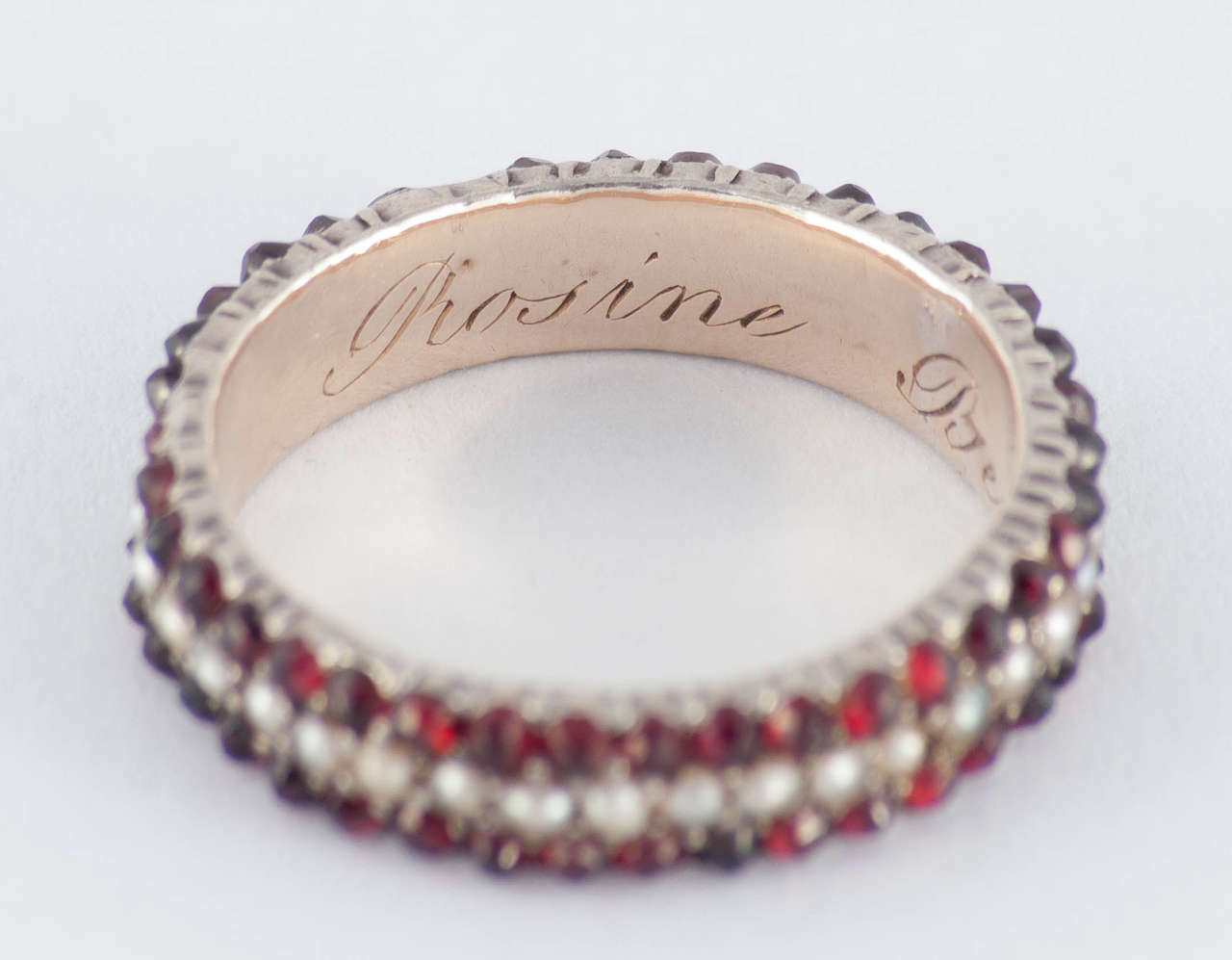 Lovely early Victorian gold and silver eternity band set with garnets and pearls. The interior is engraved with the owners name, Rosine Bennet. The ring is a size 8 and measures 3/16 in width.