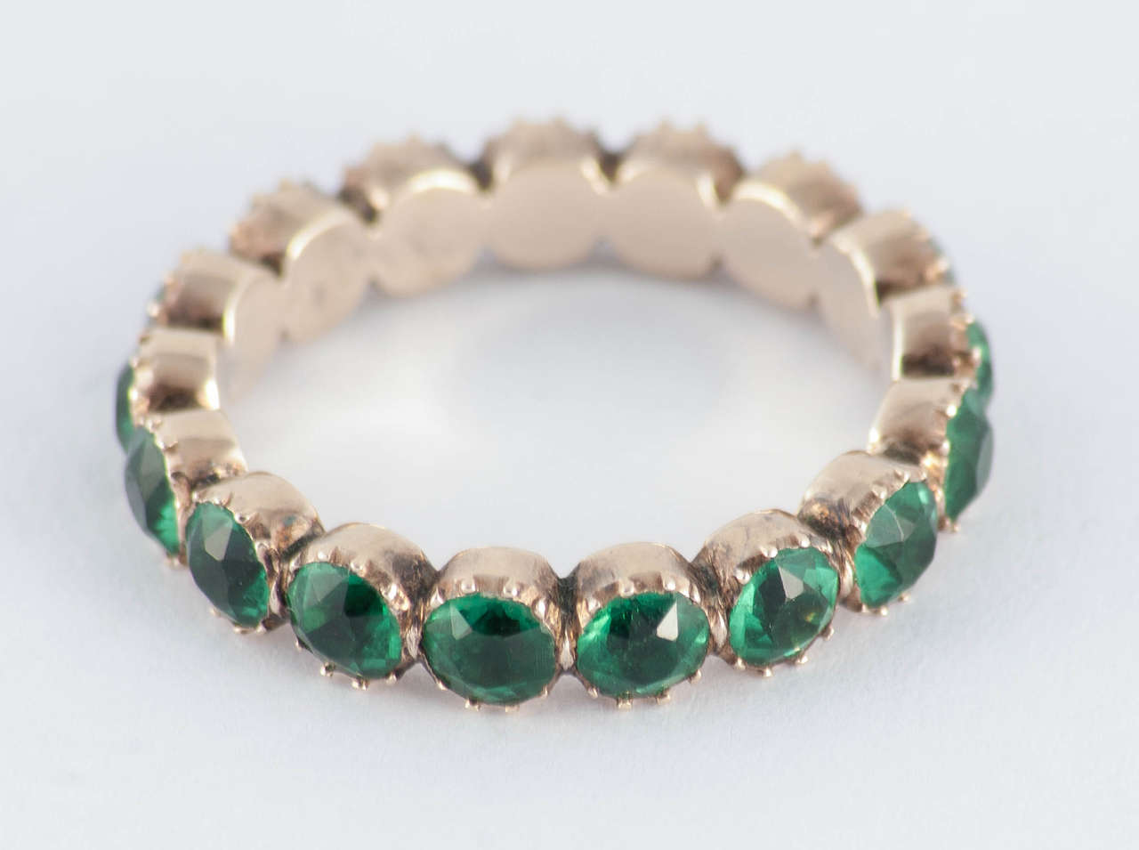 Georgian green paste eternity band in 15K gold. Paste is colored or clear glass, often lead or flint, cut in the same fashion as gemstones and used as a substitute especially when traveling. Antique paste jewelry was valued on its own merits and not