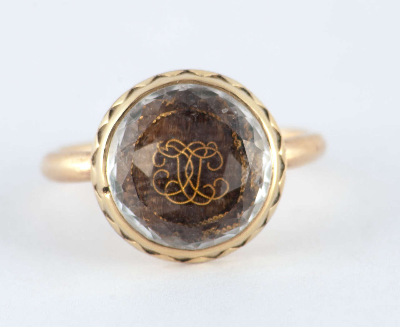 Wonderful early ring from the Stuart period in England. A faceted crystal covers plaited hair adorned by chains of gold and the golden initials 