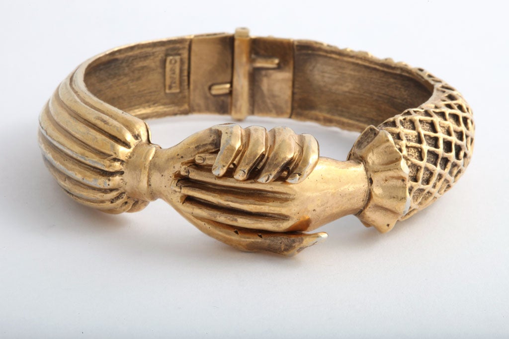 Clasping hands, hinged cuff created by Diane love in 1973 for<br />
Trifari. Gilt sculpted metal.