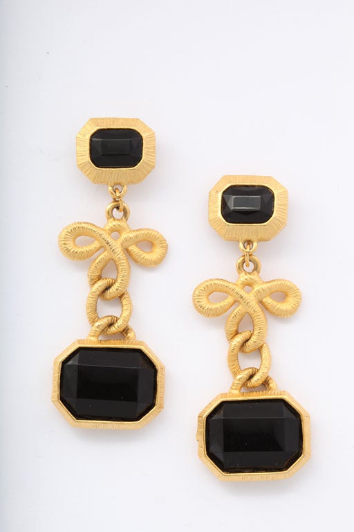Striated gold finish dangle earrings with faceted black stones.