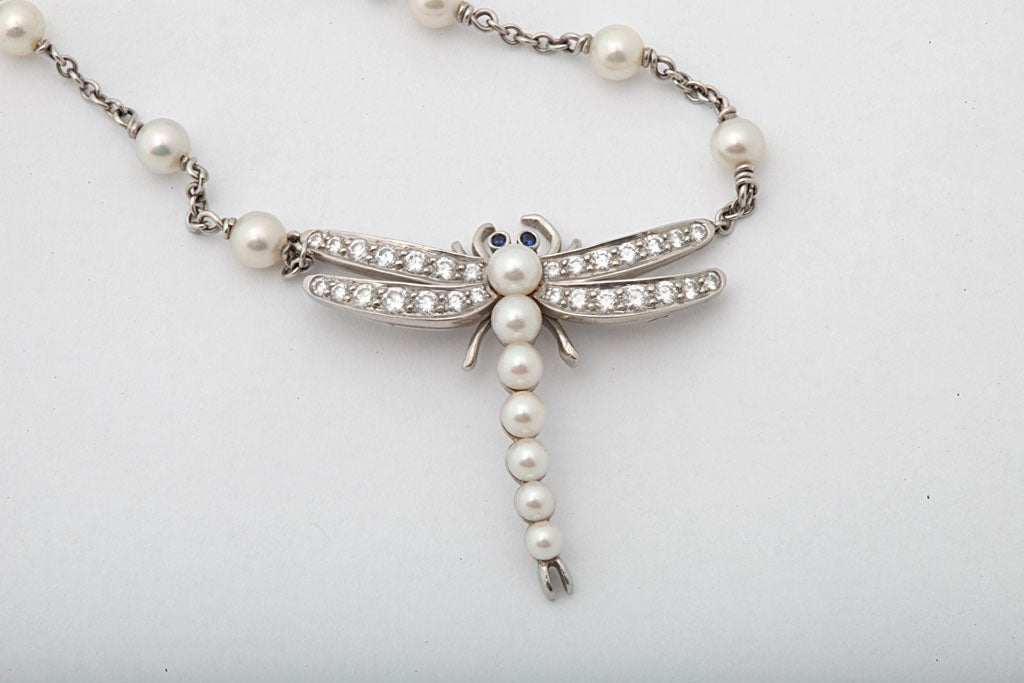 high quality platinum and diamond pendant necklace in form of a dragonfly with high quality and high lustre pearls embellished by sapphires and full cut diamonds  attached by a pearl and platinum chain