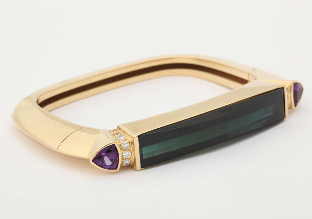 18kt yellow gold handcuff bangle bracelet consisting of 1 high quality custom cut faceted rectangular green tourmaline and further embellished with 2 triangular cut amethysts and numerous high quality full cut diamonds mounted on a very geometric