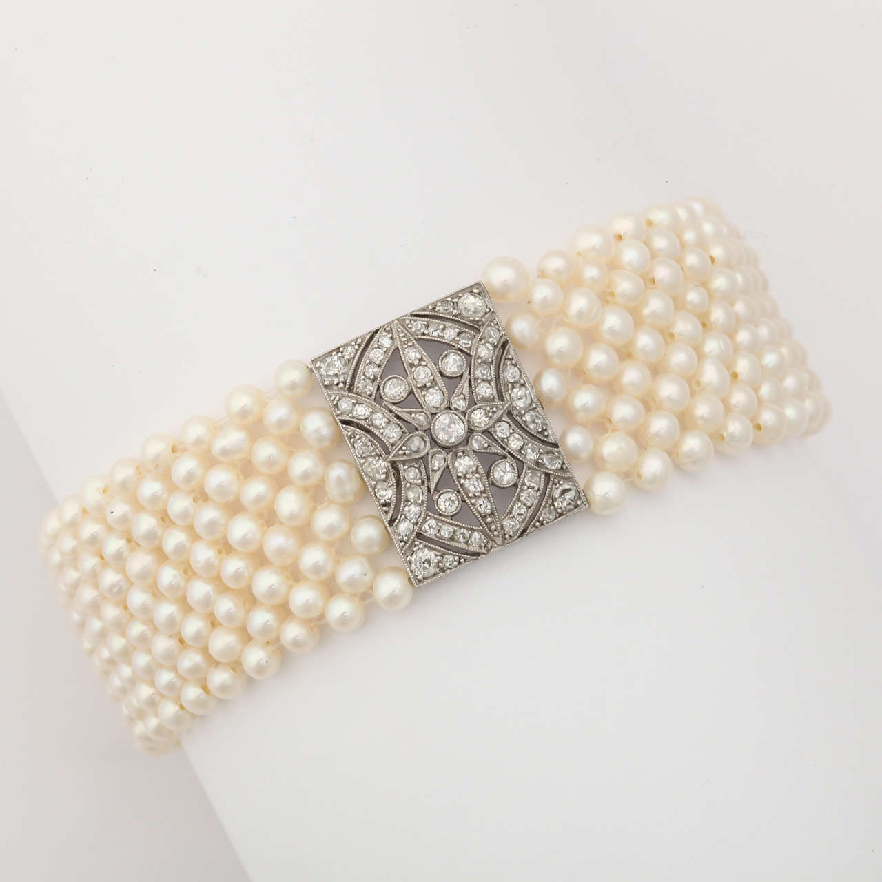 Classic in its design, this delicate bracelet features many 2mm tiny cultured high quality pearls and a wonderful platinum and diamond slide clasp. The center of the bracelet features a beautiful open work diamond & platinum rectangular plaque
