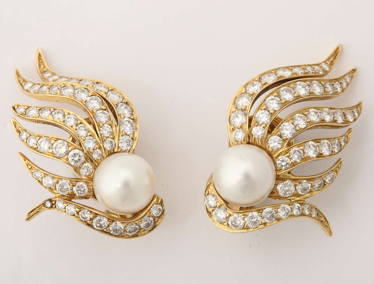 18 KT Yellow Gold Flame Design Earclips Consisting of numerous Full Cut Diamonds Weighing Approximately 4 Carats & Further Embellished by (2) 7mm High Quality Cultured Pearls in Center of Earring. 

Designed by Seaman Schepps in the 1980s