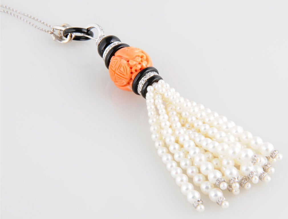 Carved coral piece highlighted by diamond and onyx accents on diamond and 18k white gold chain with a cultured pearl tassel.  18
