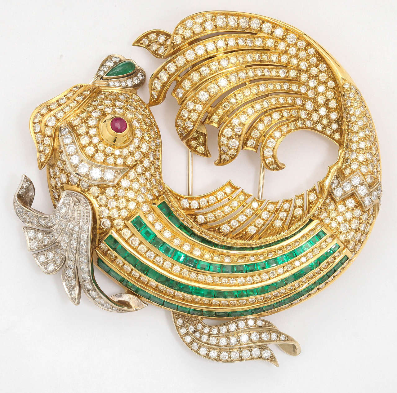 The fish is pave-set throughout with brilliant-cut diamonds, step-cut emerald and decorated with a cabochon ruby eye.