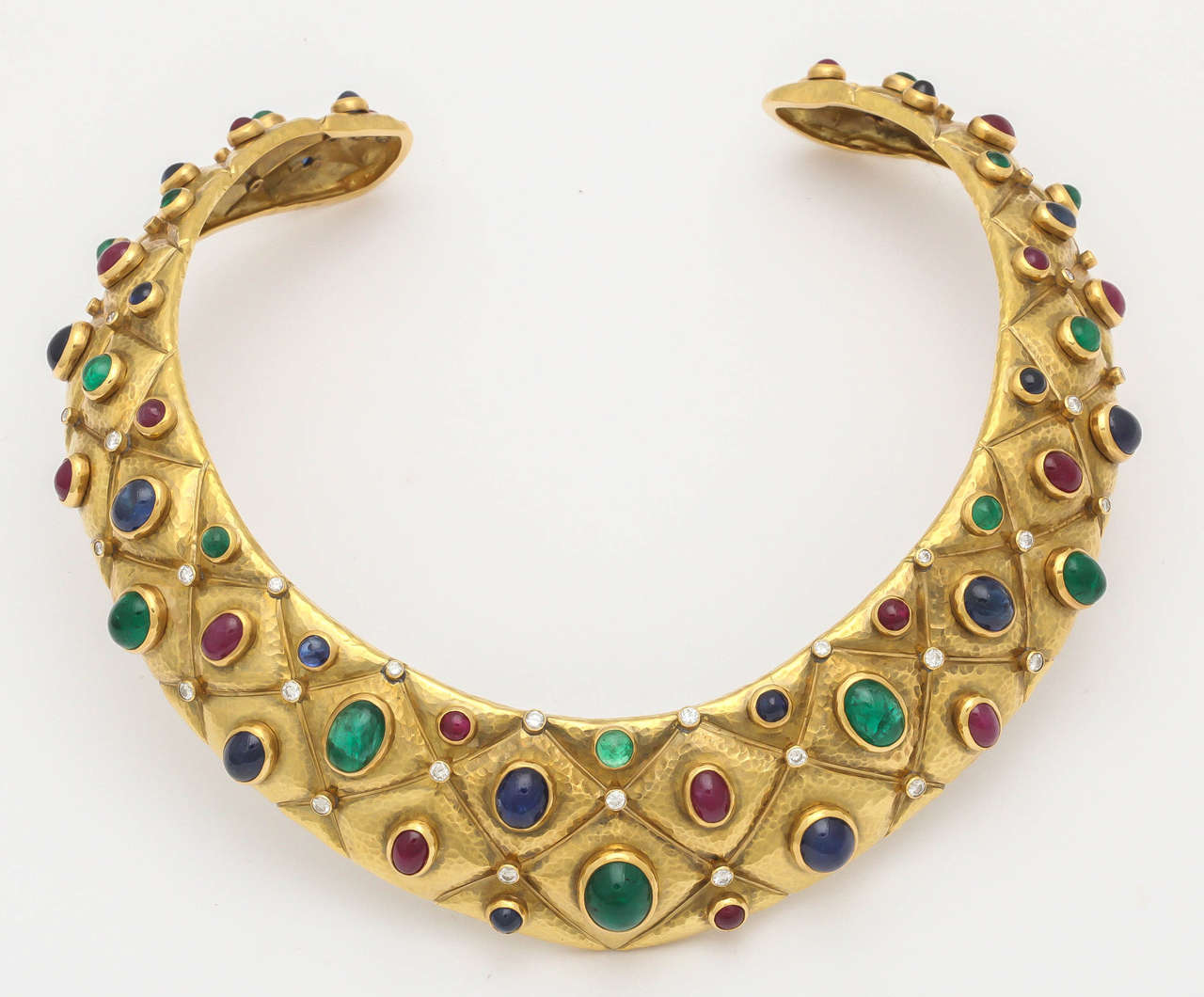 The open hammered Gold choker is encrusted with oval and circular cabochon rubies, emeralds, sapphires and brilliant-cut diamonds.diamonds weighing 1.85ct, rubies weighing15.95ct, sapphires weighing 24.10emeralds weighing 18.75ct.