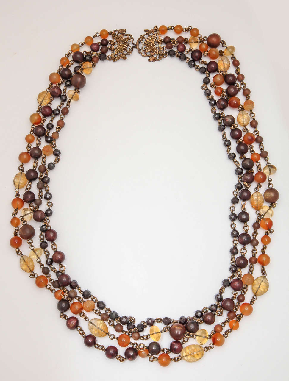Way ahead of his time & back in style again. Four graduated strands of stone beads connected by brass links hanging from a signature  Clasp.  Combination of agate beads, carved carnelian and carved Citrine, Polished orb beads, as well as faceted