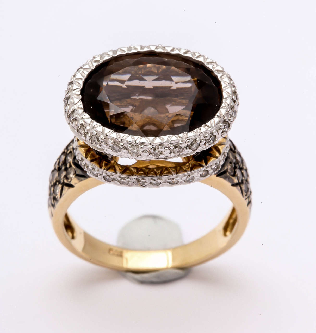 This fun smoky topaz - 6.24 ct, ring is set with white diamonds around the center stone and at the base of the stone. The topaz is set high so that light can reflect under the stone and increase it's sparkle. The sides are pave set with .55 ct. of