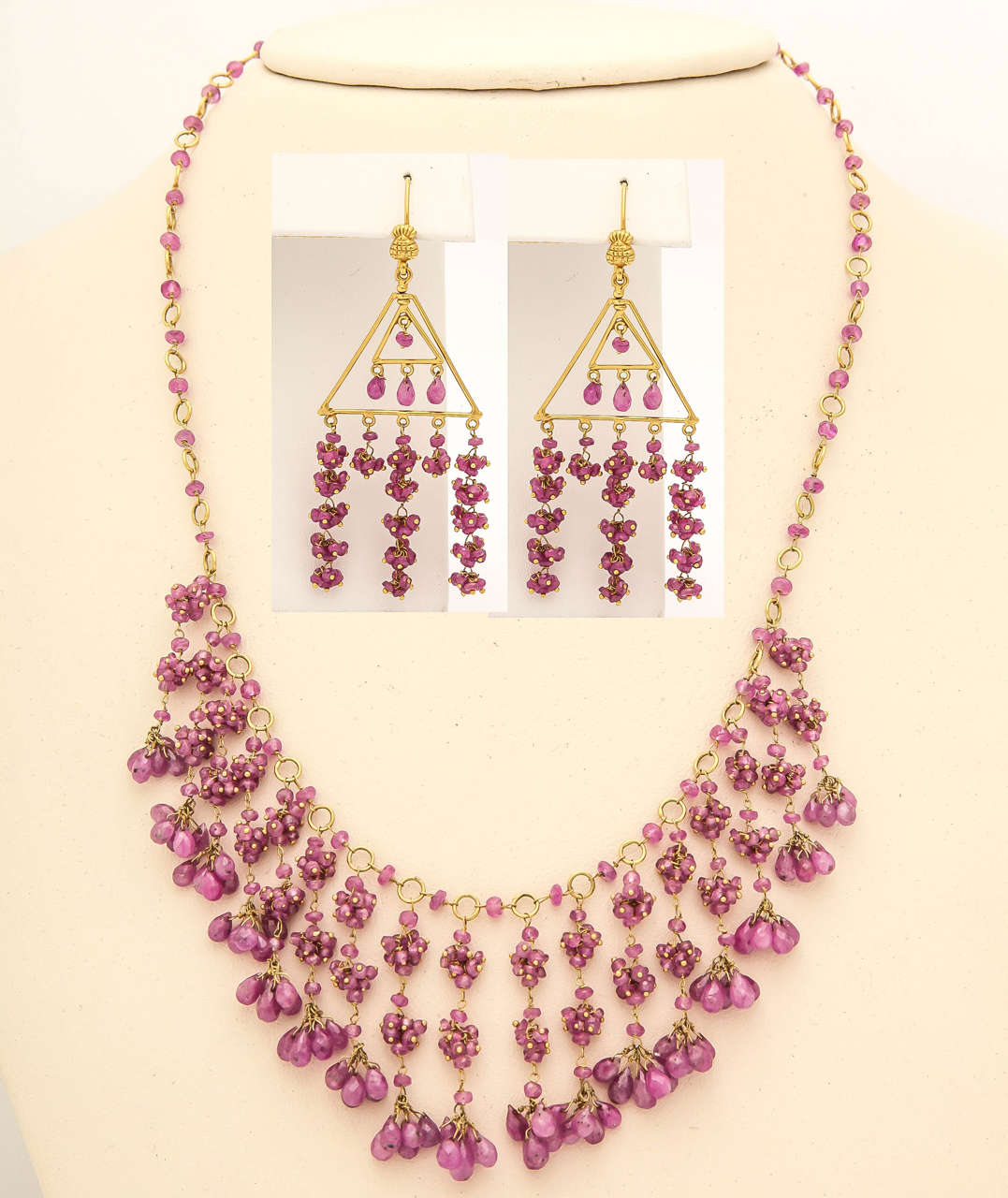 This delicate ruby/pink sapphire bead necklace and earring set is all hand wired in 18 kt yellow gold. The dangles are clusters of ruby beads with ruby briolettes on the end of each unit. This necklace and earrings moves beautifully and create and