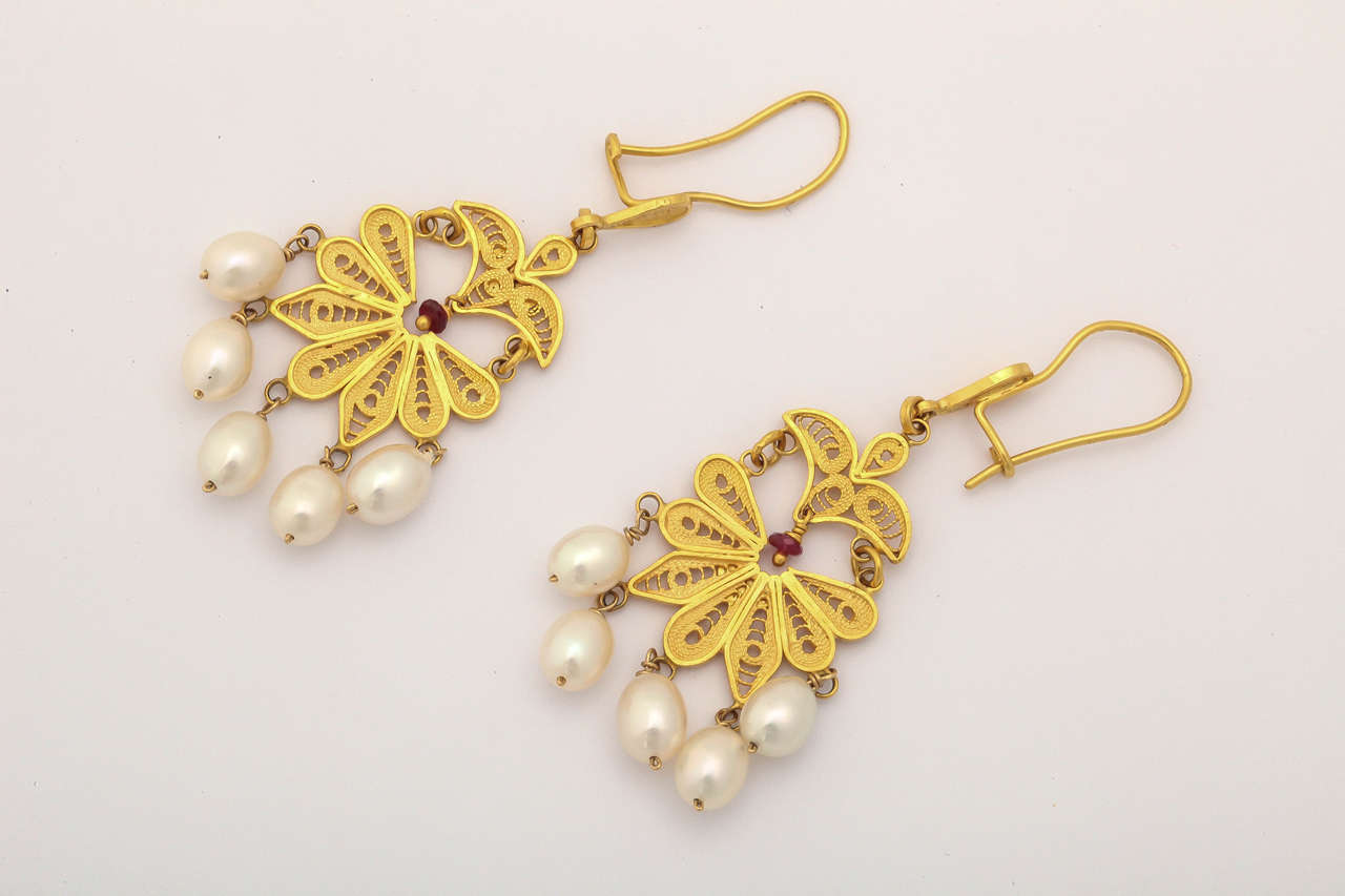 These earrings are hand made of fine individual wires fused together in a classical Greek-Middle Eastern style. They are rich 22 kt gold with a small dangling ruby bead in the center and fresh water pearls gracefully suspended from the bottom of the