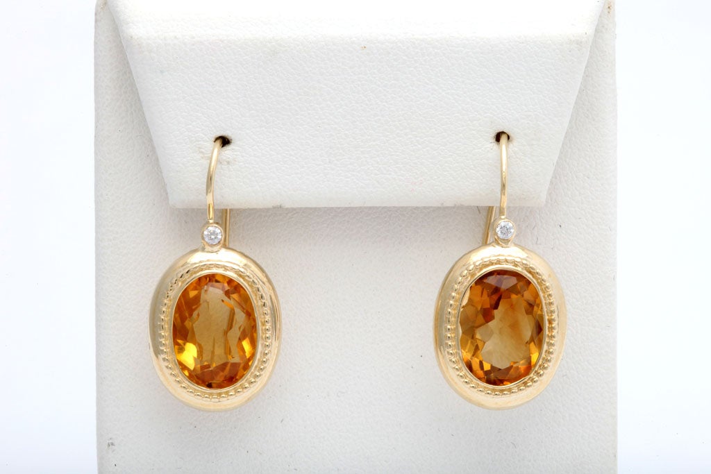 Lovely design oval frames surrounds beautifully cut citrines with a diamond at the top.