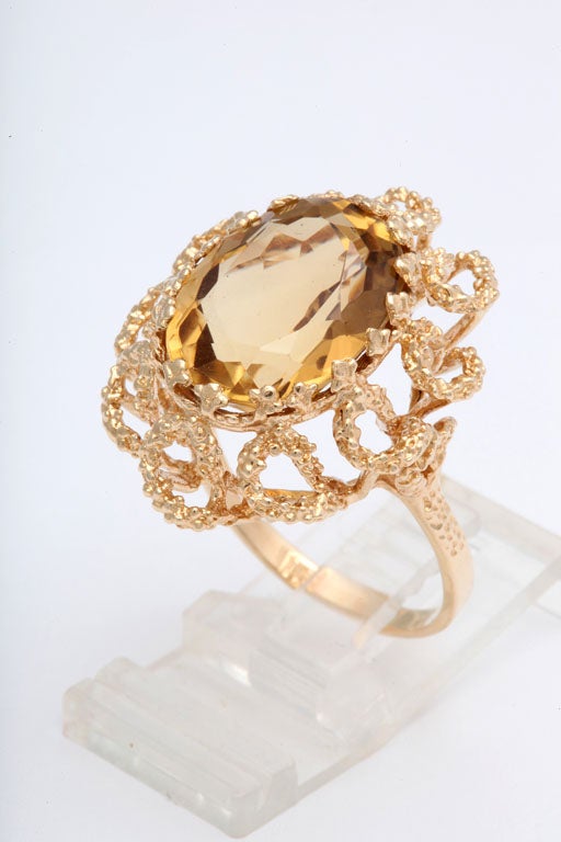Striking 1960s citrine ring featuring a large facetted oval citrine in a hand made stylized 14k yellow gold mounting.  The open gold swirls create a floral design. 
Size 10 - It can be sized.