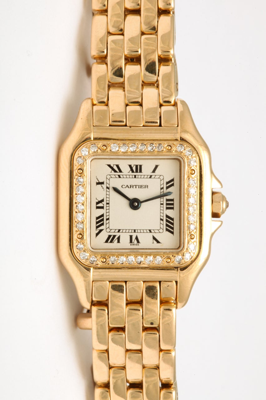 Classic Cartier lady's 18k yellow gold Panthere wristwatch featuring a white dial with black Roman numerals, sapphire crystal and blue sapphire cabochon in the crown. Trouble-free Cartier quartz movement, double deployment buckle.
