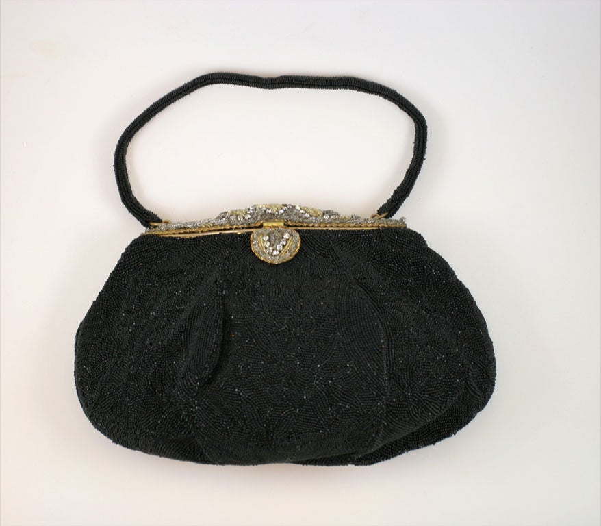Made in France for Saks Fifth Avenue this black beaded bag is circa 1940's. The frame of the bag is clear crystal and gold beads with a pattern of rhinestones. Bag is lined in black satin.<br />
<br />
The beading is done in a black-on-black