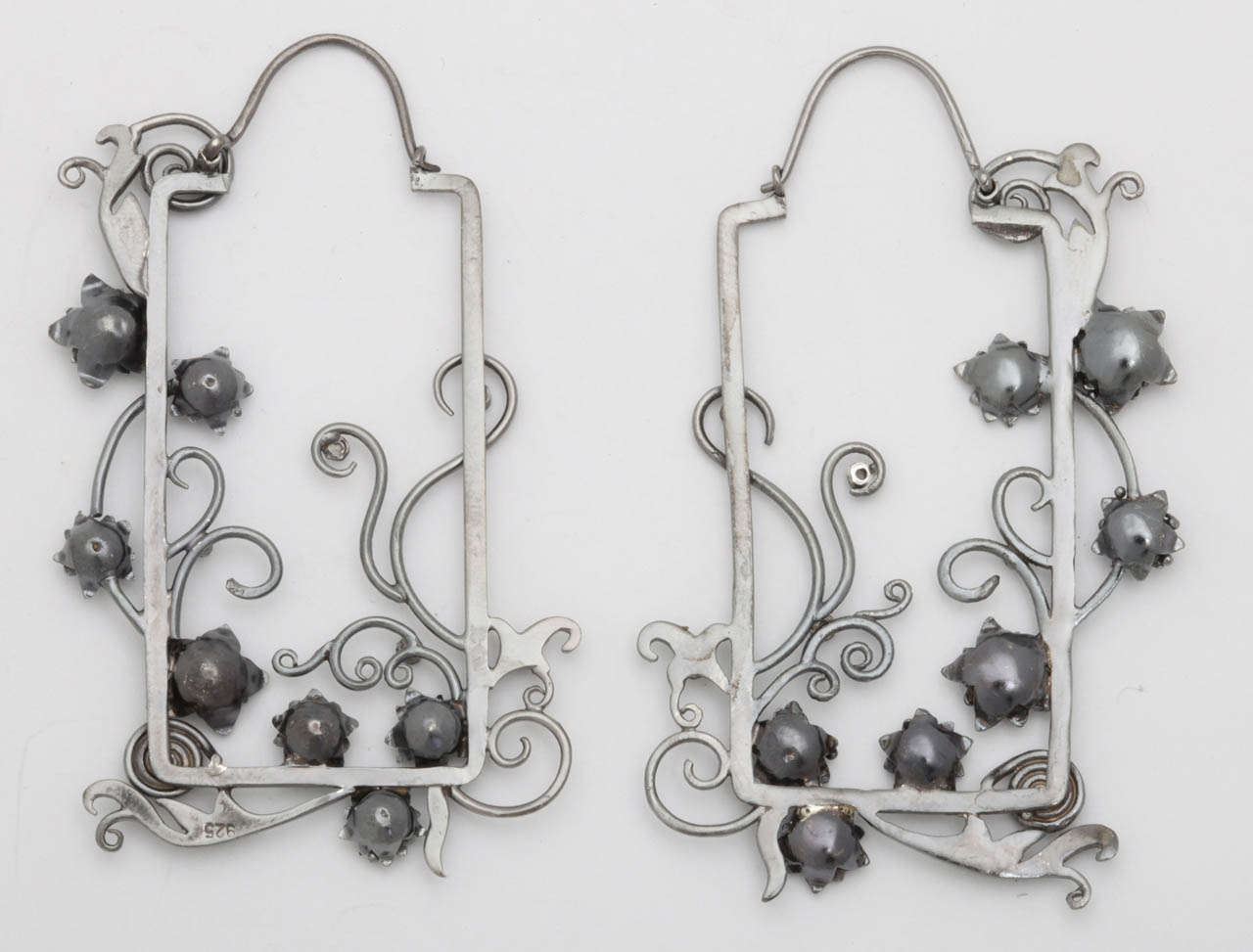 A pair of sterling silver and diamond window pane earrings. The panes are decorated with creeping sterling vines and flowers. There are bezel set diamonds in the center of each flower.