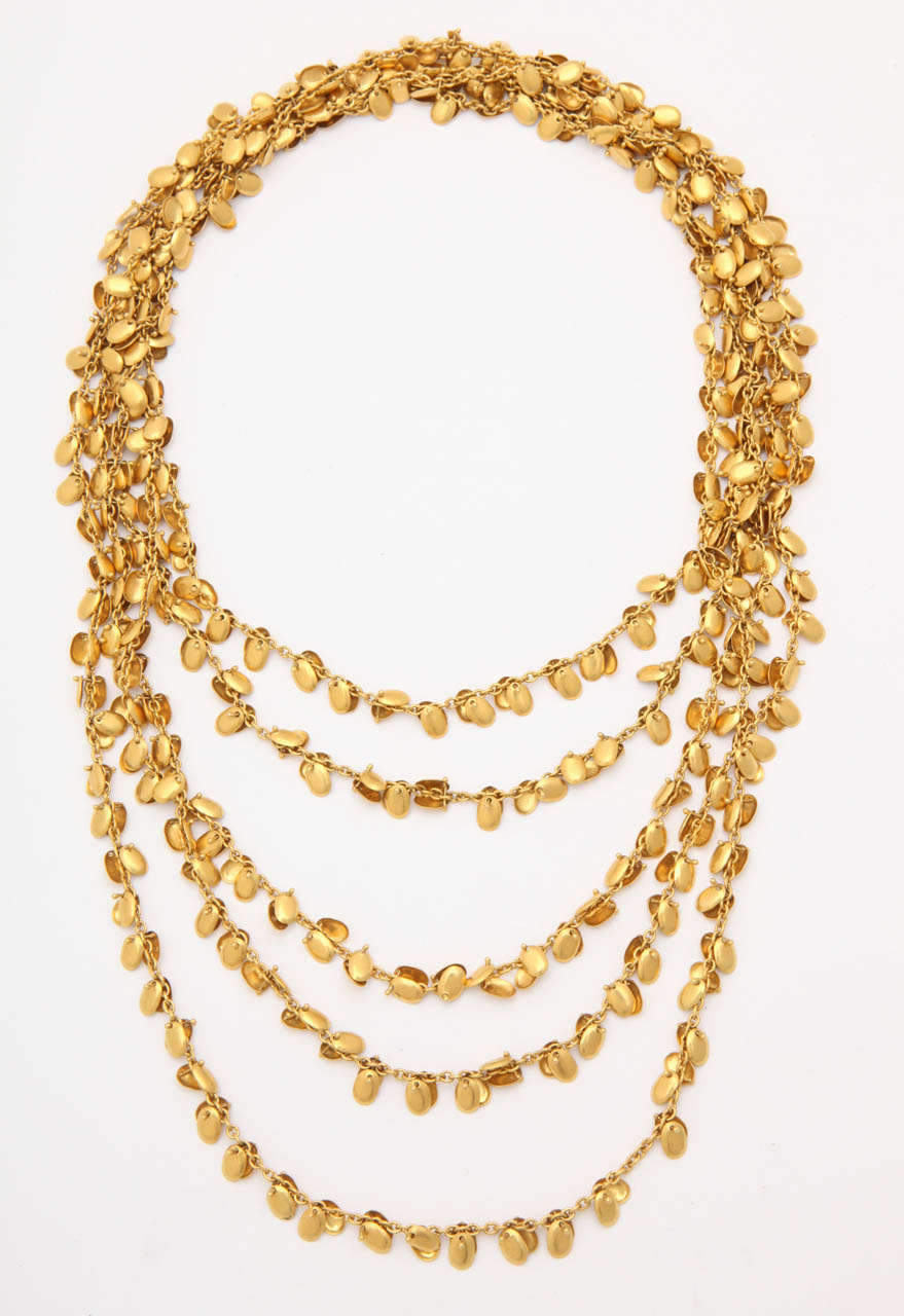 a handmade 18kt yellow gold necklace. The necklace is composed of two chains that are interspersed with riveted concave oval discs.