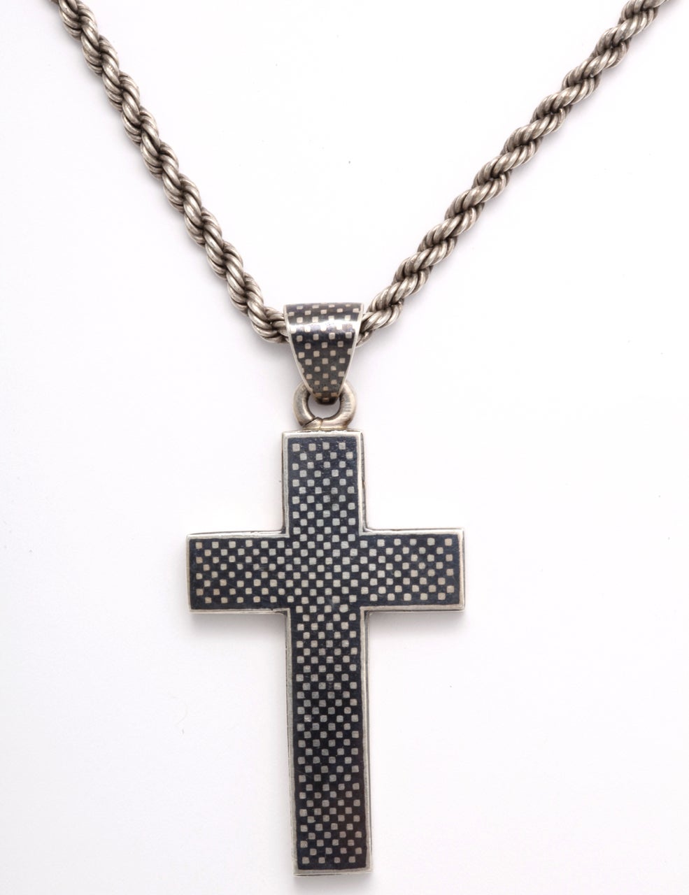 All geometry, this simple cross is covered at front with minute squares of silver. In the late Victorian period, French and Russian jewelers made pieces using a silver technique known as niello. They heated, to melting, a mixture of silver, copper,