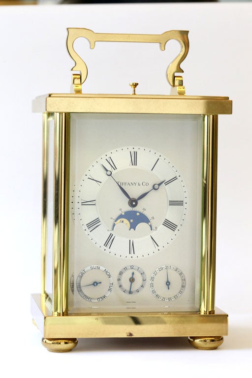 Handsome Swiss brass and enamel carriage clock for Tiffany & Co,  late 20th century, is a triple date alarm calendar moonphase clock. It features a two-tone matte and silvered dial, painted black Roman numerals, moonphase at 6 o'clock, the three