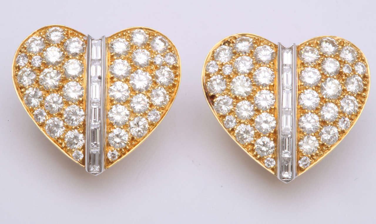 18k Yellow Gold heart earrings featuring 68 round diamonds, 5.80 carats, and 12 baguette diamonds weighing 0.99 carats.