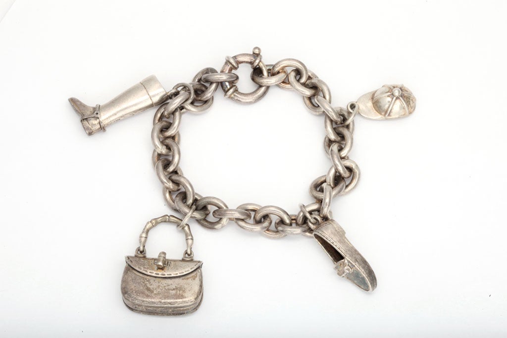 Very chic Bracelet with four iconic Charms hanging from a heavy oval link Chain and ending  with a large spring ring closing.  The charms are: Leather Boot, Leather Loafer, Pocketbook & Riding Cap. Signed Gucci, Italy, 925 & Control Marks.