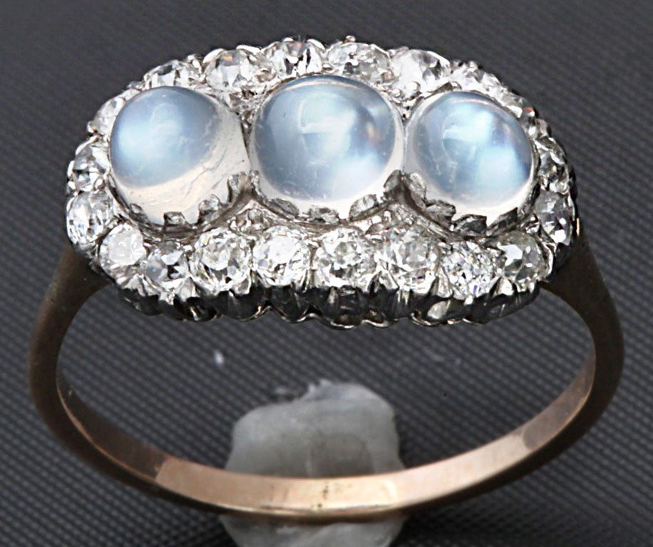 Three blue cabouchon moonstones meet your gaze from their nest of 19 old mine and european cut diamonds. Total diamond weight approximately .50 cts. Total moonstone weight is approximately 1.60 cts. Platinum holds the stones while the shank is gold.