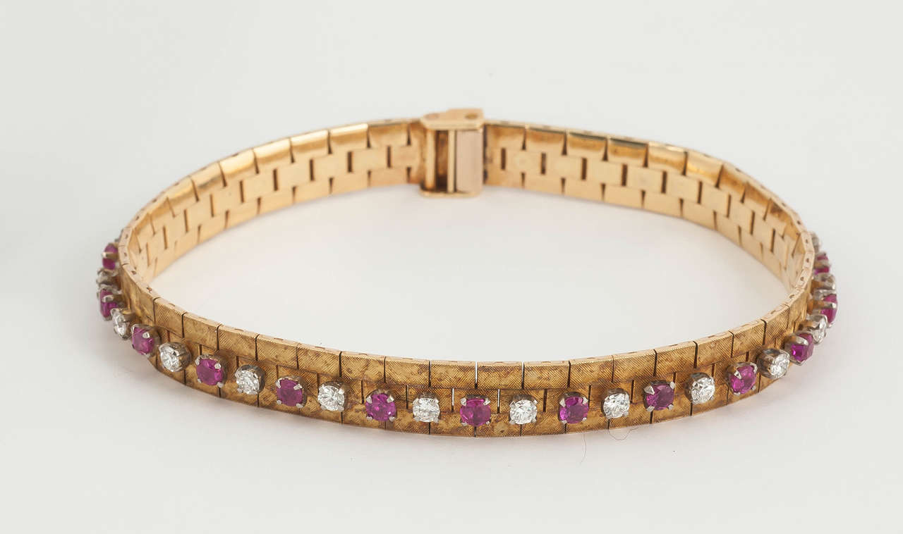 A finely made 18 carat yellow gold bracelet with a textured finish in a soft patina, set with alternate Burma rubies and brilliant cut diamonds. English hallmarked for 1965.
Measures 9mm in width x 13cm in length.
Vintage piece in the Victorian