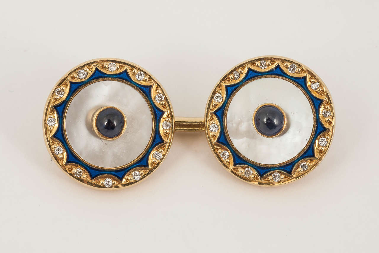 Pair of 18 ct yellow gold mounted cufflinks with a cabochon shaped sapphire centre within Mother of pearl, surrounded by blue enamel and edged with diamonds. Signed Dunhill ( Alfred Dunhill) English c 1965-70
