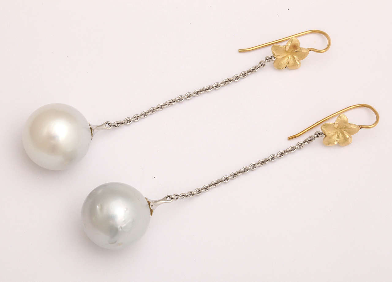 These long, dangly, fun earrings feature a 17-18mm South Sea pearls, a 14 kt yellow gold flower connected by a 2 in. 14 white gold cable chain. Total length 3 1/2 in. The ear wire is extra long for safety and stability.