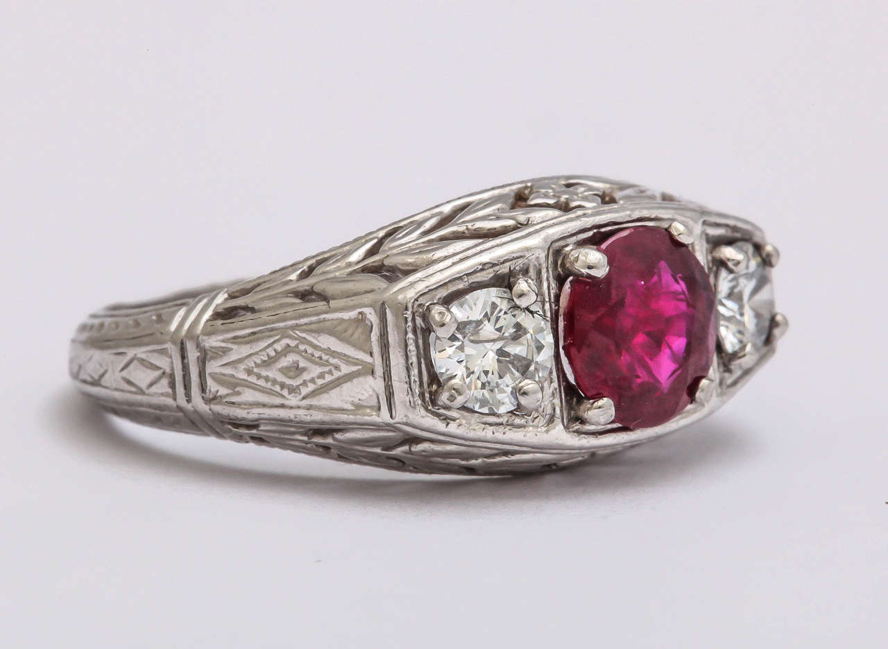 The finely crafted ring ,in the 'turn of the century' style,  features 1.4 ct fine ruby and 2 round diamonds  on either side weighing .66 ct total. The 14 kt white gold is  finely hand engraved all around the ring including the shank. Ruby is the