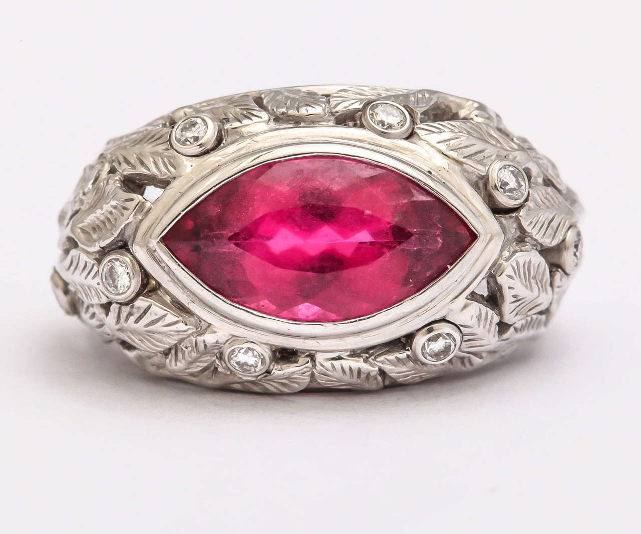 This beautiful and rare hot, hot pink tourmaline marquis weights 3.34 cts.  and measures 15 mm long and 8 mm. wide.  It is bezel set in 14 kt white gold with 9 bezel set diamonds weighing .24 ct. The white gold makes the bright pink color POP!