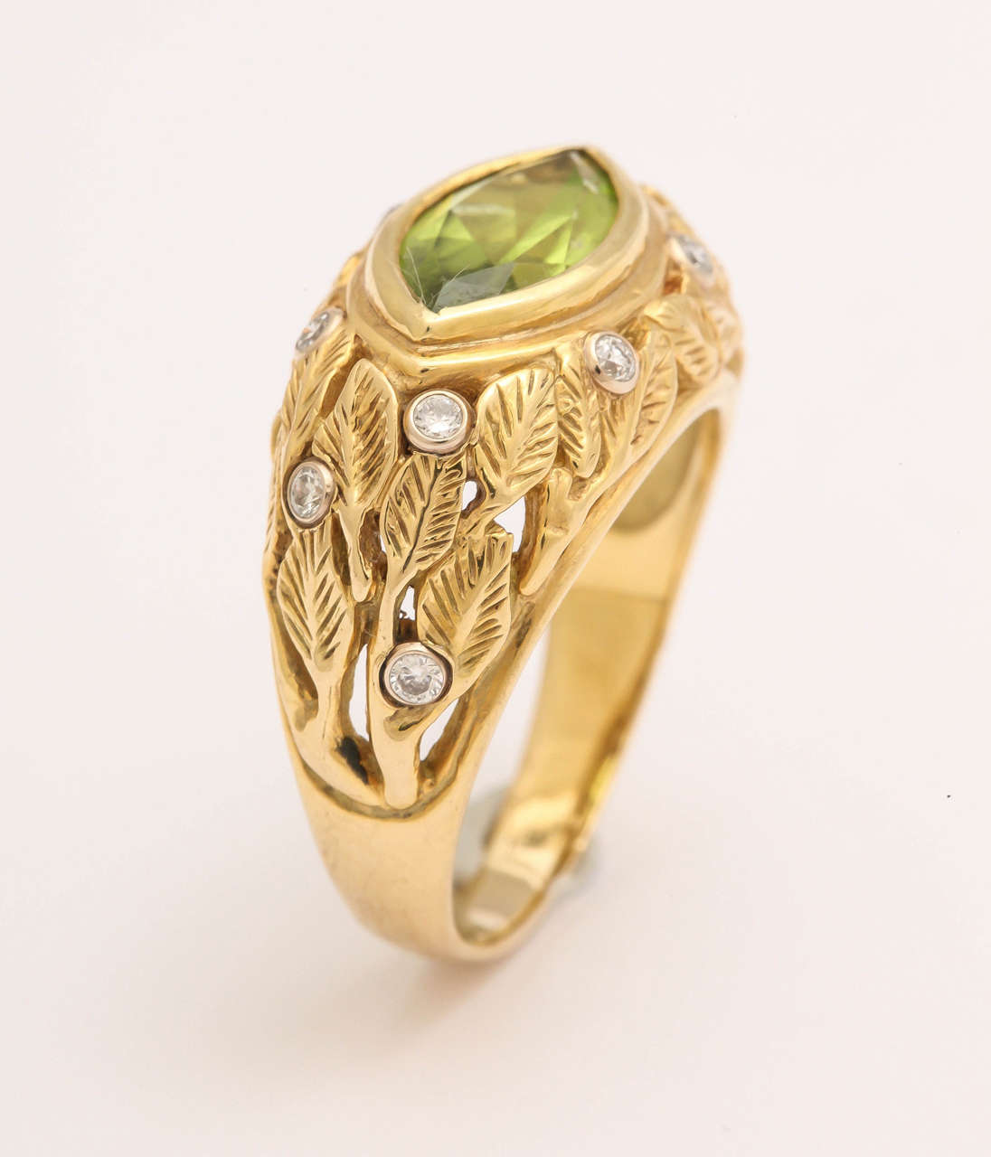 The leaf pattern compliments the rich green of the marquise peridot center stone, weighing 2.76 cts and measuring 7mm x 14 mm. Scattered among the leaves are  9 platinum bezel set round white diamonds weighing .27 cts. The ring is 8 1/2 and can be