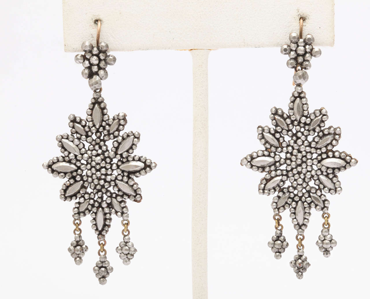 A lush example of Georgian chandelier earning, is intricate and artfully made of the tiniest bits of hand cut, diamond like cut steel c.1830. The earrings are semi abstract flowers with three girandole drops. All arts other than the oval petals are