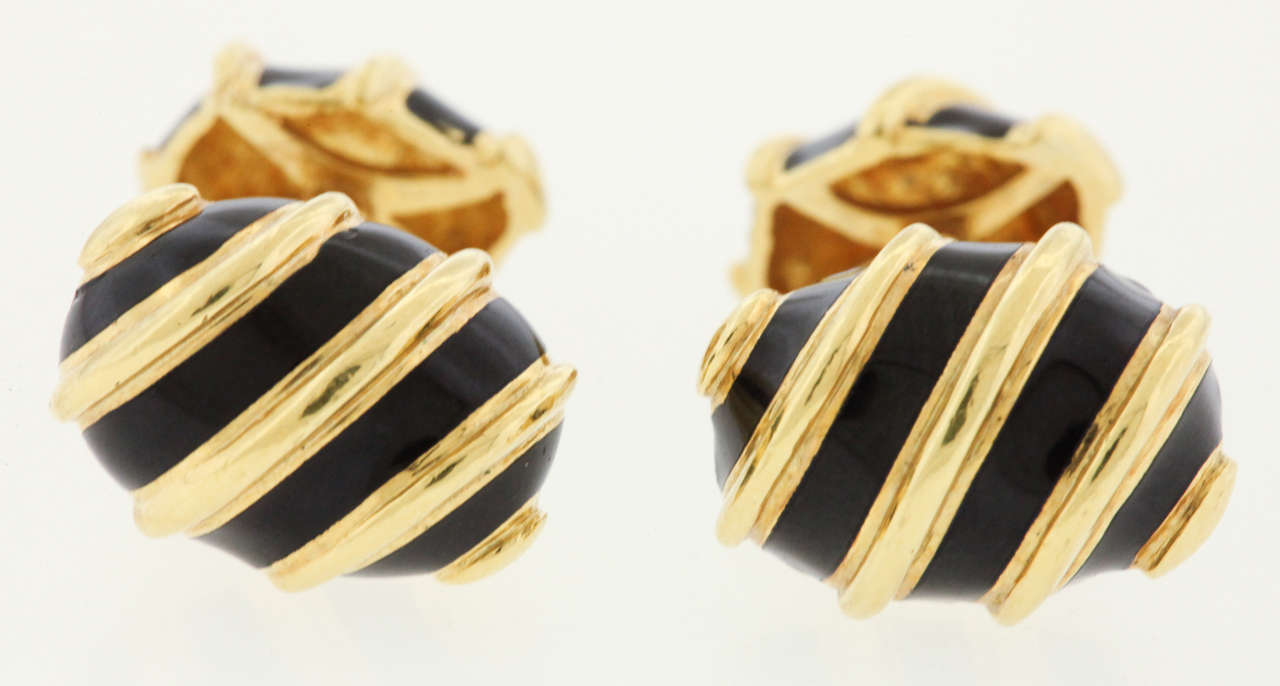 A pair of 18K gold and black enamel cufflinks by Jean Schlumberger, Tiffany & Co., circa 1990's, are each designed as a black enamel and  fluted gold bombe scroll, joined by a polished gold bar to a link of similar design, mounted in 18k gold.