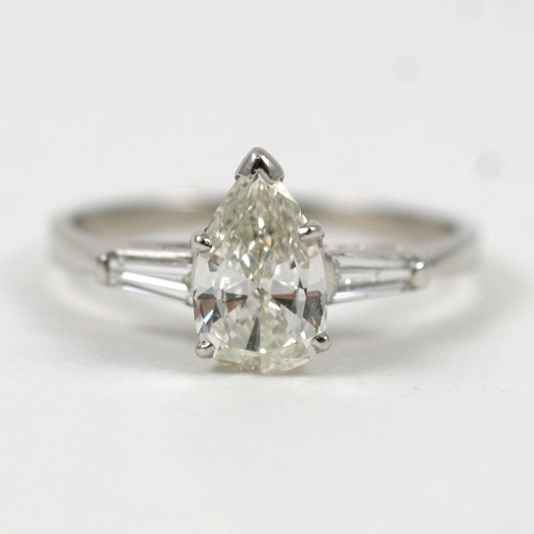 Platinum engagement ring featuring one pear shaped diamond weighing appox. 1.10 carats, Color: I-J, Clarity: VS, flanked with 2 tapered baguettes, 0.30 atw.