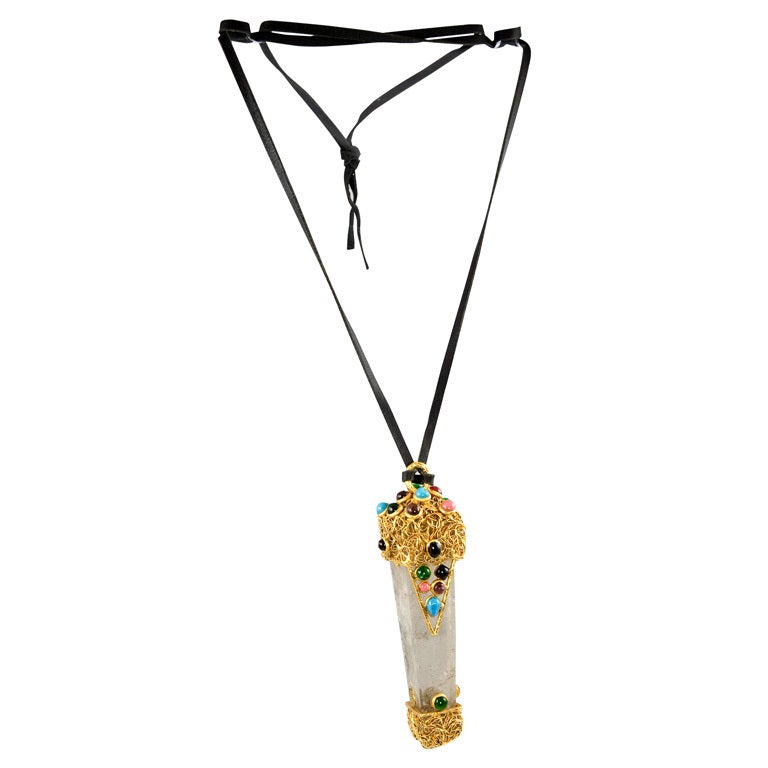 Very rare and unusual pendant consisting of a polished shard of Rock Crystal that is capped by gold tone metal and set with poured glass stones.  The pendant is suspended on a black leather cord.  This is a unique example and a runway piece. 