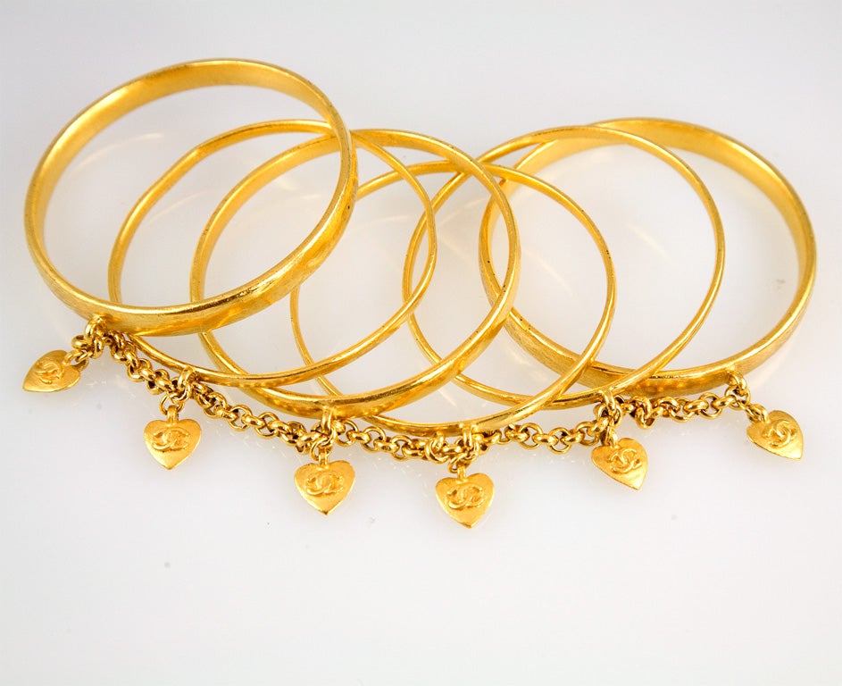 Fantastic set of six gold plated bangles of varying thickness joined together by chain and finished off with the addition of a locking Cs heart.