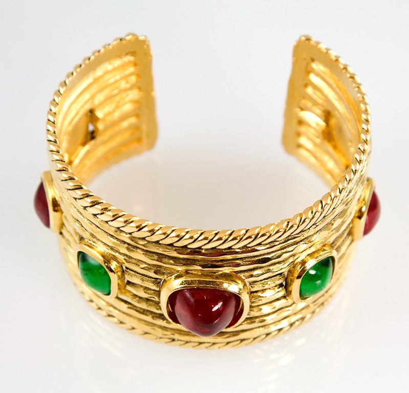 Beautiful and striking wide gold plated cuff by Chanel with bezel set ruby red and emerald green poured glass stones. Marked on the back with the 