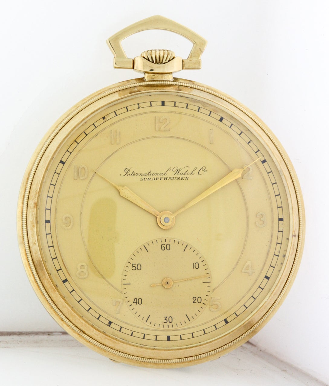 14k yellow gold open face IWC pocketwatch, made for the American market, circa 1940s. It has a 50mm case with beaded bezel, engine-turned striped back, inner cuvette, gilt movement, two-tone champagne target dial with outer minutes chapter, applied