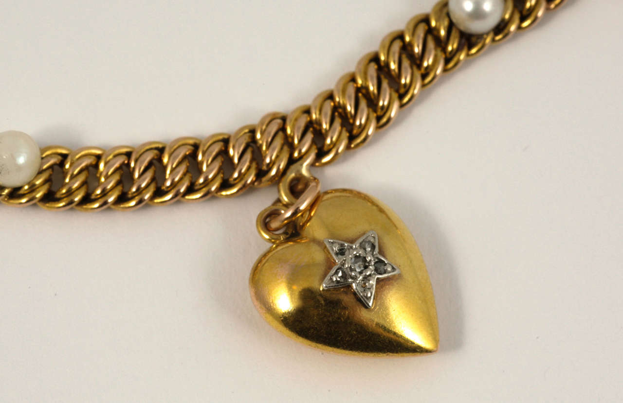 18ct yellow gold and pearl charm bracelet with French hallmarks. 
The bracelet is double link curb. 
The charms are all original. There is a heart ( not a locket), a poodle, a violin and a glass double sided locket (can put photos back to