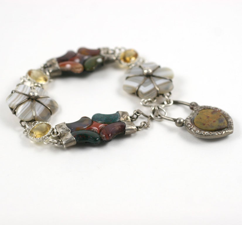 We offer a striking, antique scottish floral design bracelet of both abstract and realistic design,  with alternating flowers of montrose gray agate and rich toned scuptural, curved budding blooms. To spark the above are silver links centered by