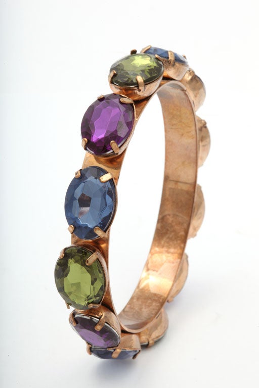 Round goldtone bangle bracelet with prong set oval rhinestones in green, blue, and purple.