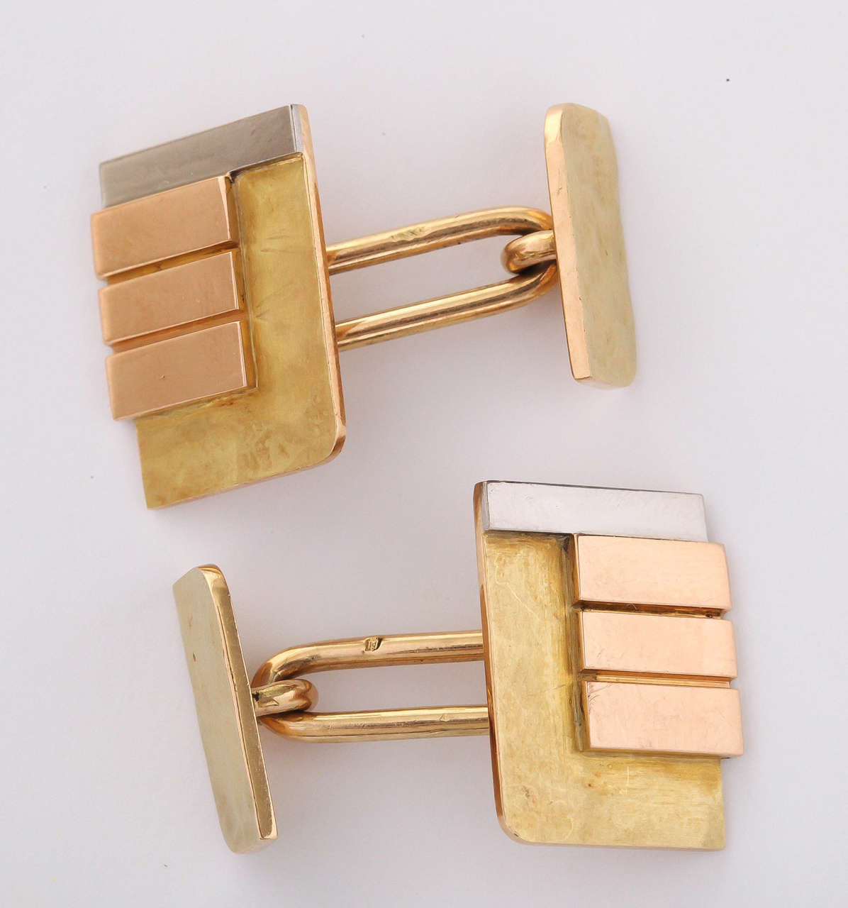 The martele base in yellow gold has applied to a triple bar in rose gold and a rectangular rod in white gold attached by an oval ring to the small side with martele surface and square corners alternating with round corners.

Hallmarked for 18 kt